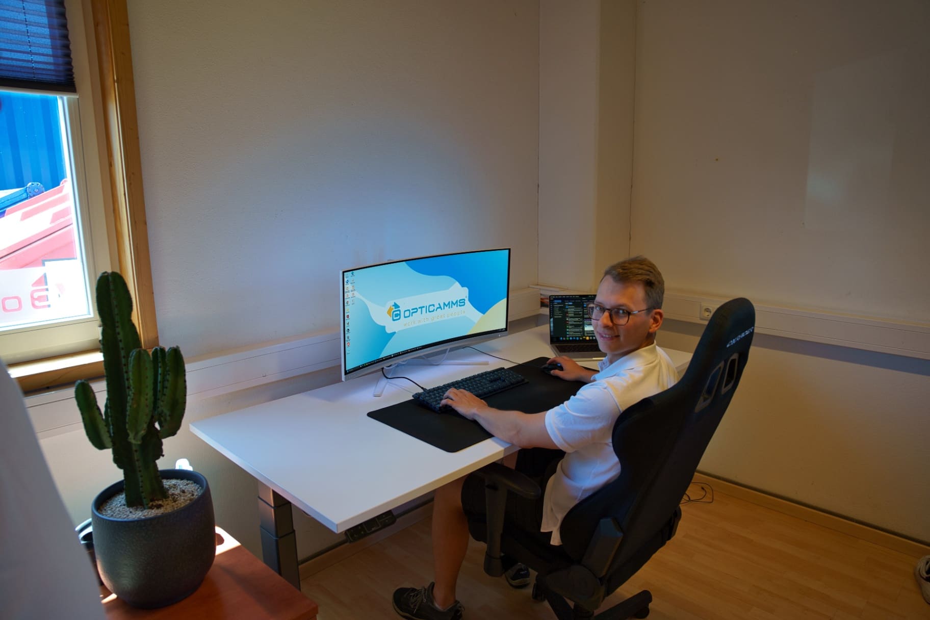 Kollege am Arbeitsplatz im Büro mit OptiCAMMS-Bildschirmhintergrund